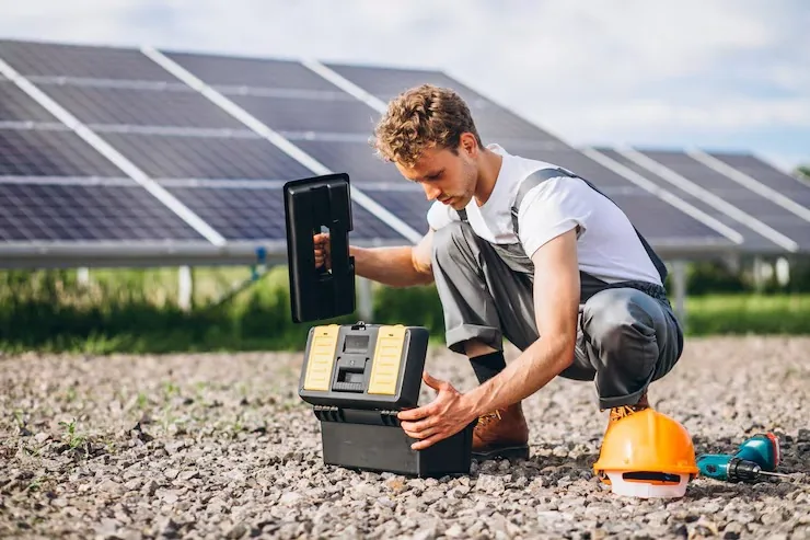 Persona de pie junto a una fila de paneles solares en el campo